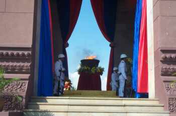 A military honor guard stands at attention near a ceremonial flame