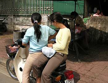 A Cambodian girl is sqeezed between a driver and a passenger of an  overloaded motorbike taxi in the capital Phnom Penh, Tuesday, April 4,  2006. Overloaded motorcycles and cars are a common