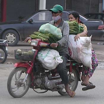 A Cambodian girl is sqeezed between a driver and a passenger of an  overloaded motorbike taxi in the capital Phnom Penh, Tuesday, April 4,  2006. Overloaded motorcycles and cars are a common