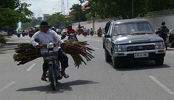 A Cambodian girl is sqeezed between a driver and a passenger of an  overloaded motorbike taxi in the capital Phnom Penh, Tuesday, April 4,  2006. Overloaded motorcycles and cars are a common