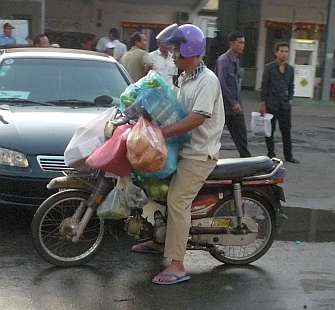 A Cambodian girl is sqeezed between a driver and a passenger of an  overloaded motorbike taxi in the capital Phnom Penh, Tuesday, April 4,  2006. Overloaded motorcycles and cars are a common