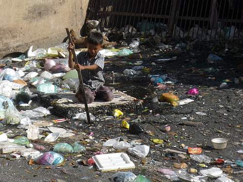 Boy paddling in open sewer