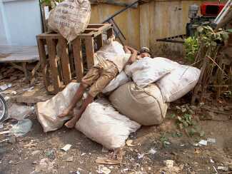 Street boy sleeping on bags of paper