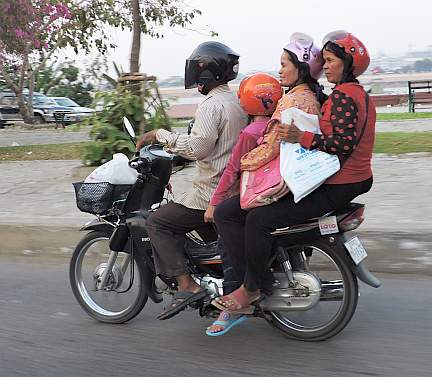 Four people with helmets on one motorcycle!